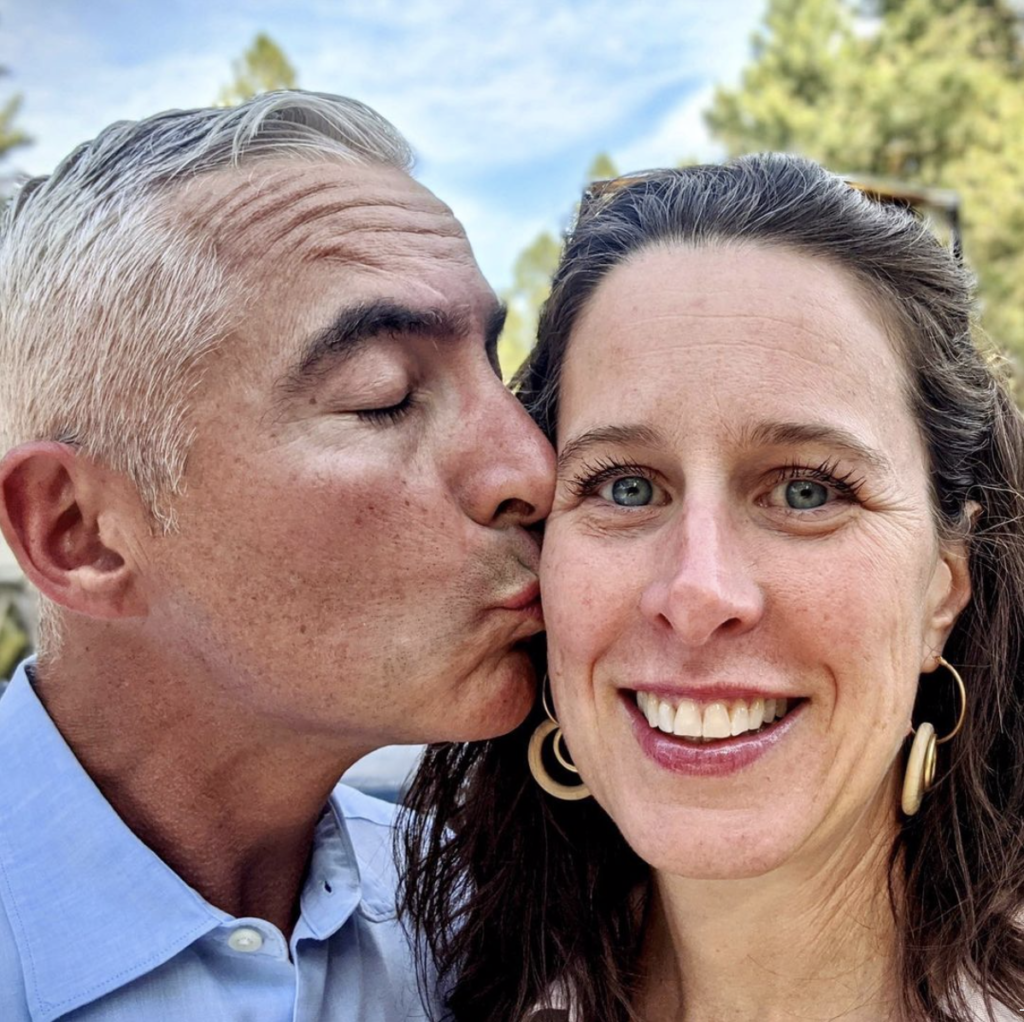 Photo of Scott kissing Christine's cheek. Christine is smiling. This is what 15 years of marriage looks like, at least on us. 