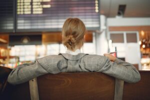 Woman sitting alone at an airport gate, looking up at the departures board